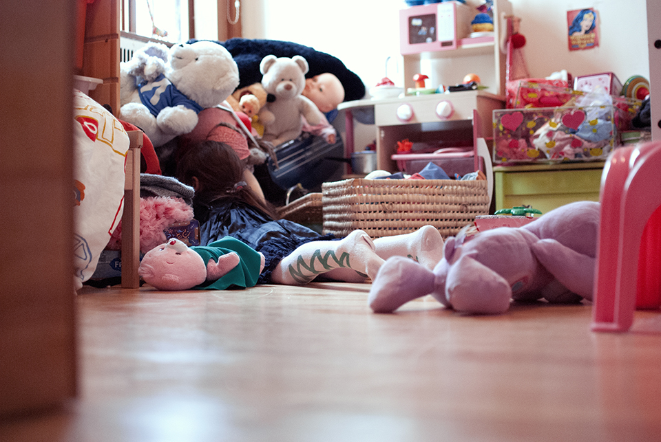 Family documentary photography, little girl under bed with stuffed animals