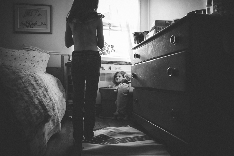 Family Documentary Photography - Black and White girl hides in laundry basket