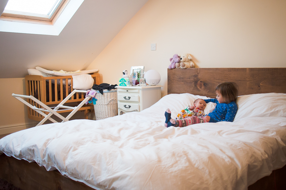 Little girl and baby on bed - Family Documentary Photography