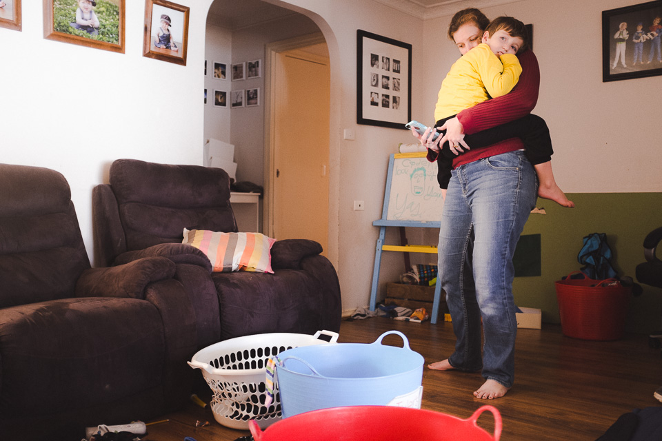 mother holds child mid laundry - family documentary photography