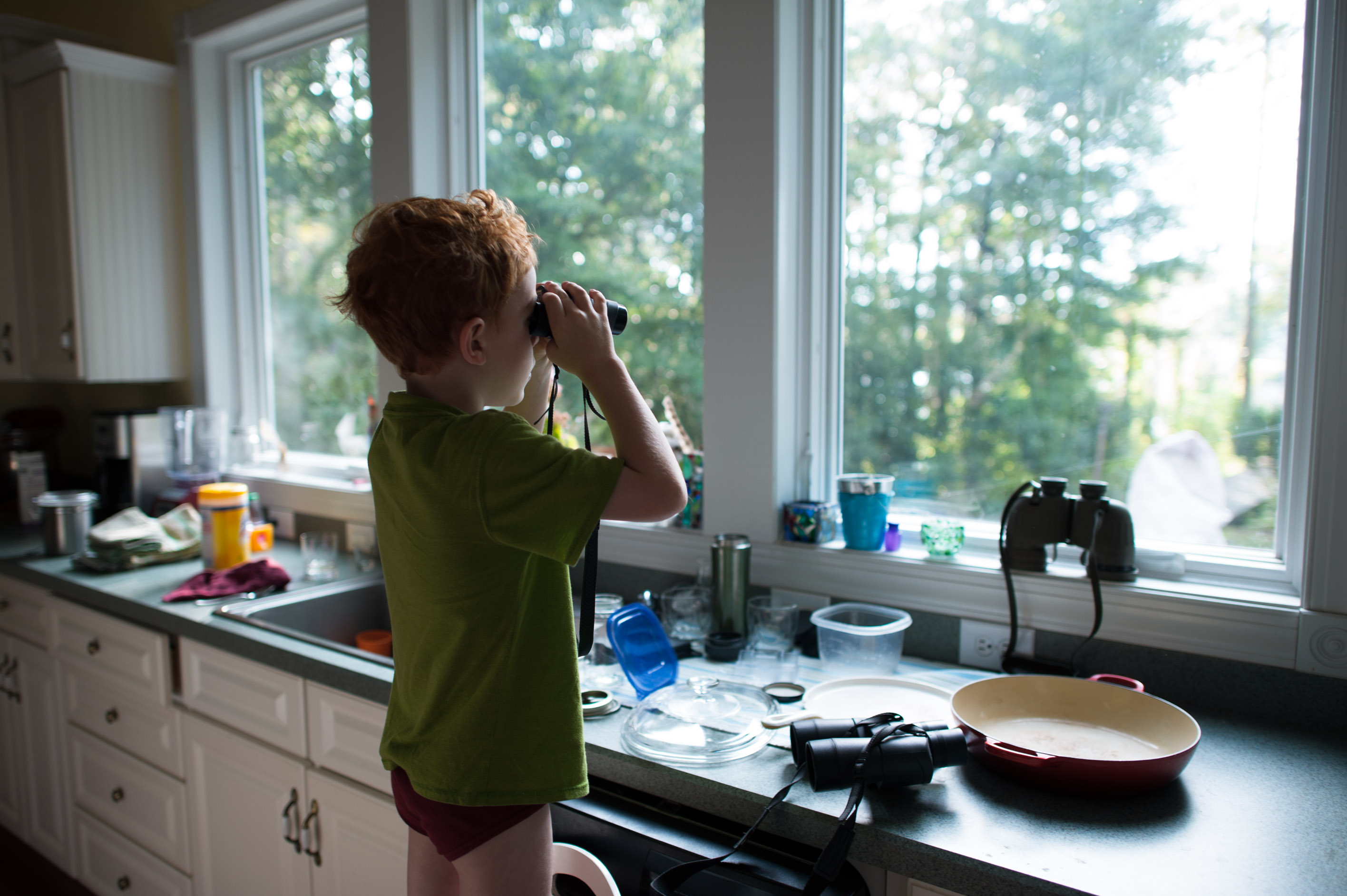 boy looks our window with binoculars - family documentary photography
