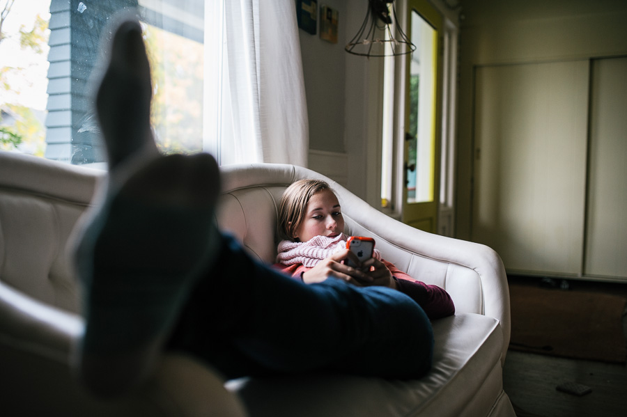 girl lounging on couch with phone - Family documentary photography