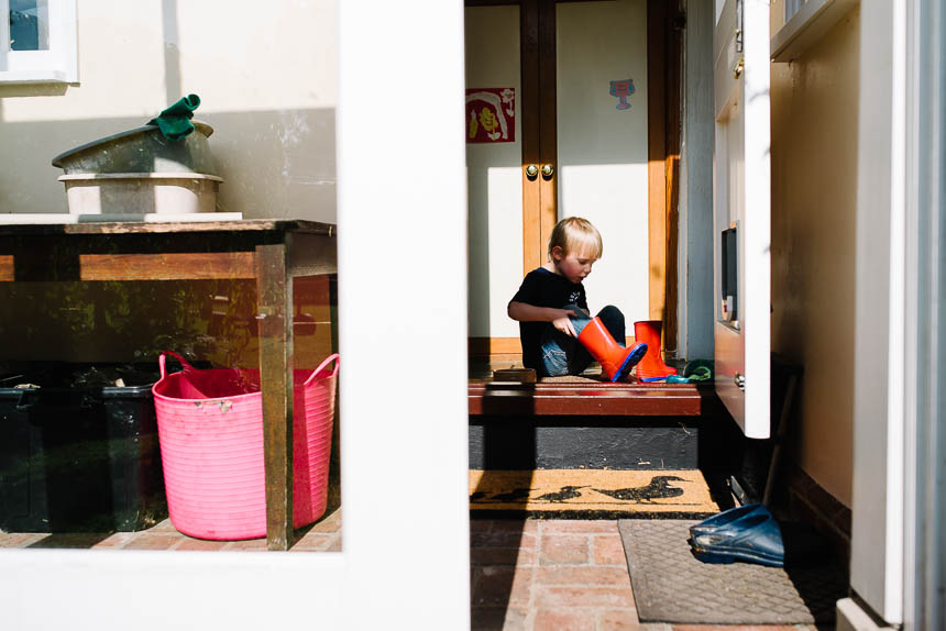 boy putting on wellies - family documentary photography