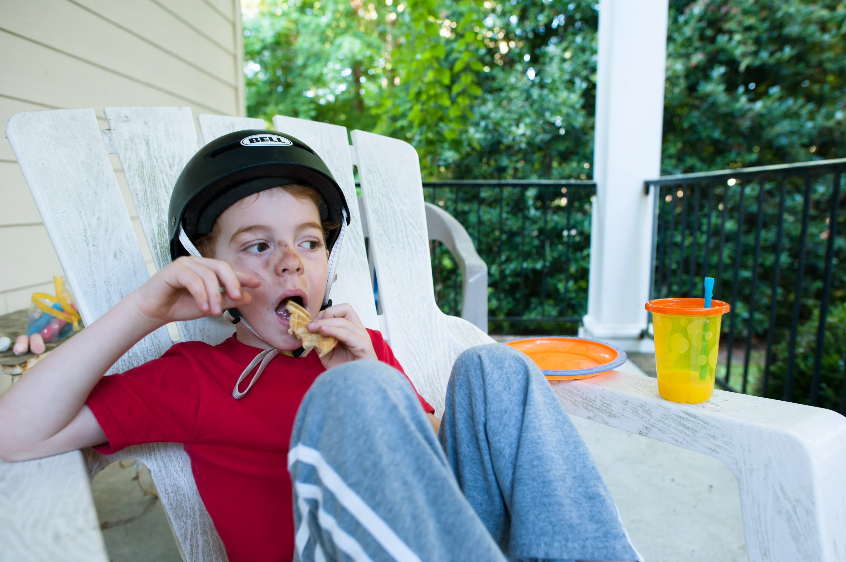 boy wearing helmet eating on porch - family documentary photography