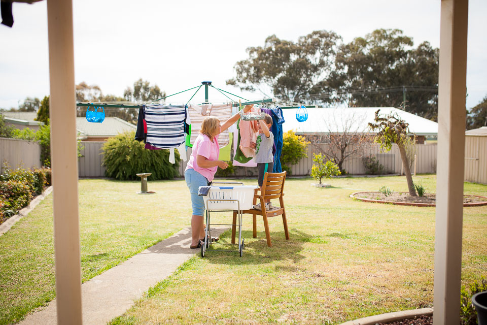boy helps hang laundry - documentary family photography
