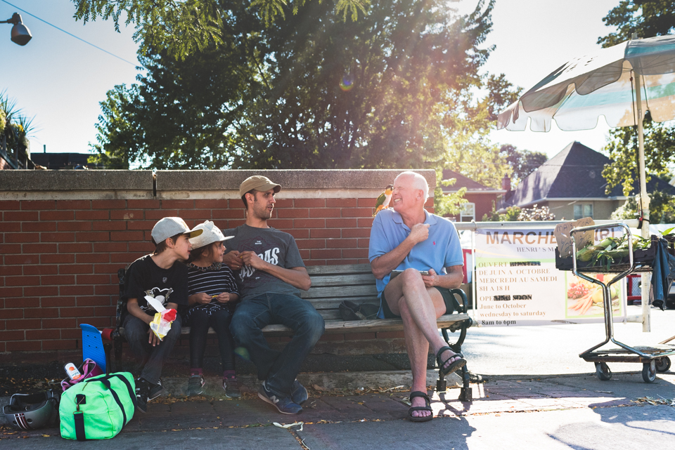 Family on park bench talks to man with pet bird - Family Documentary Photography
