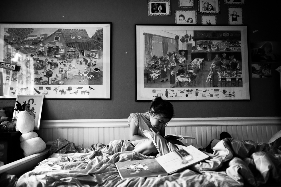girl reads book in bed - documentary family photography