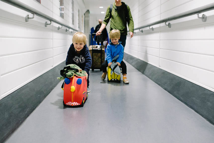 boys riding luggage in hallway - Family Documentary Photography
