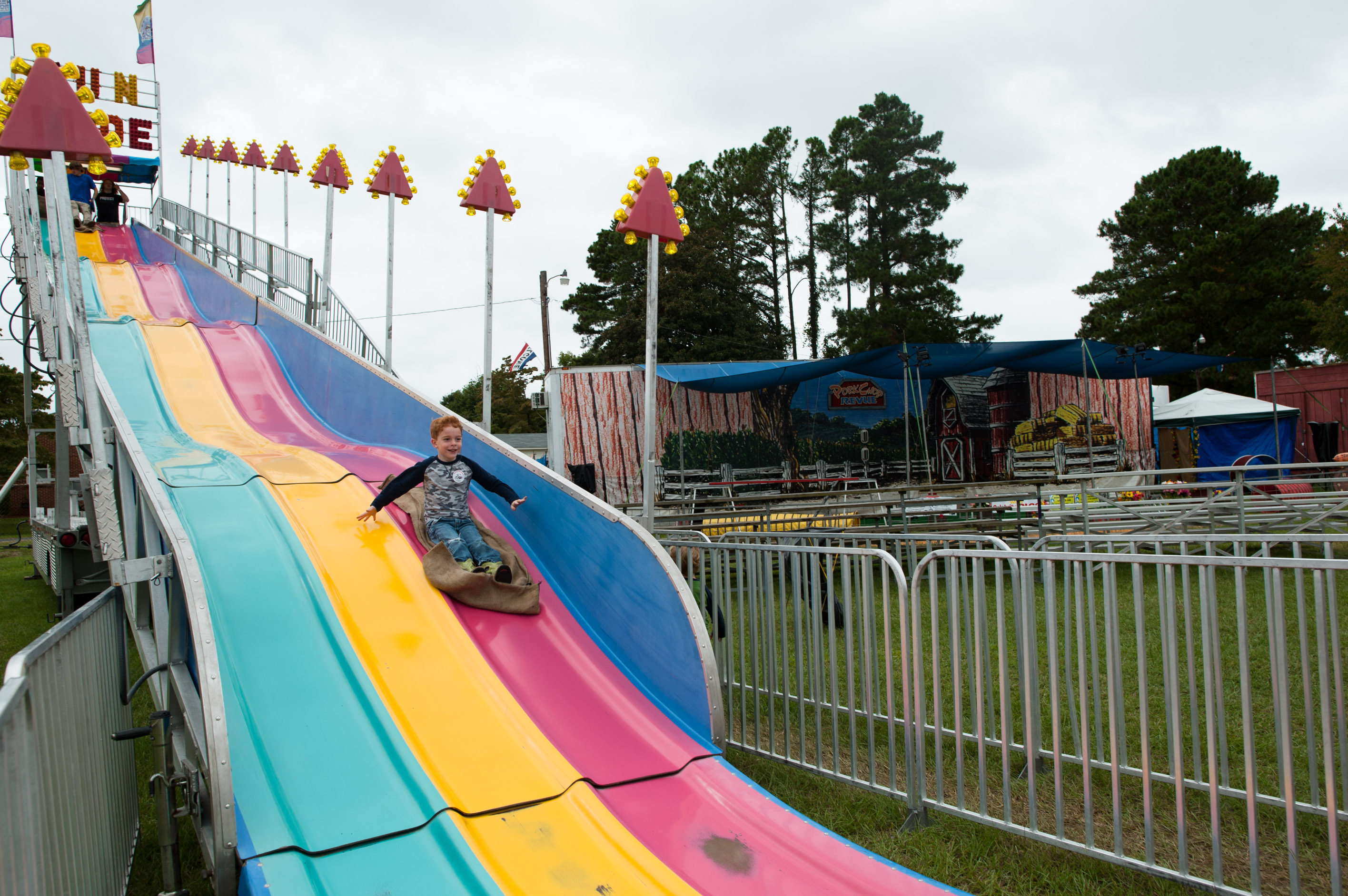 boy going down giant fair slide - Family Documentary Photography