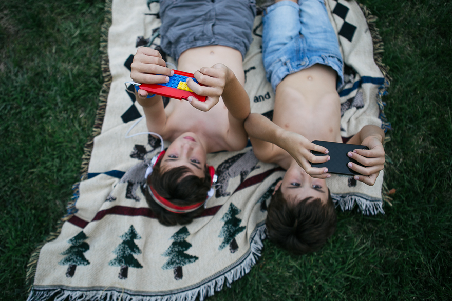 Boy in grass playing with electronics - Family Documentary Photography