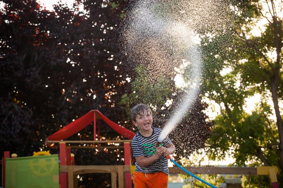 boy holding garden hose spraying water