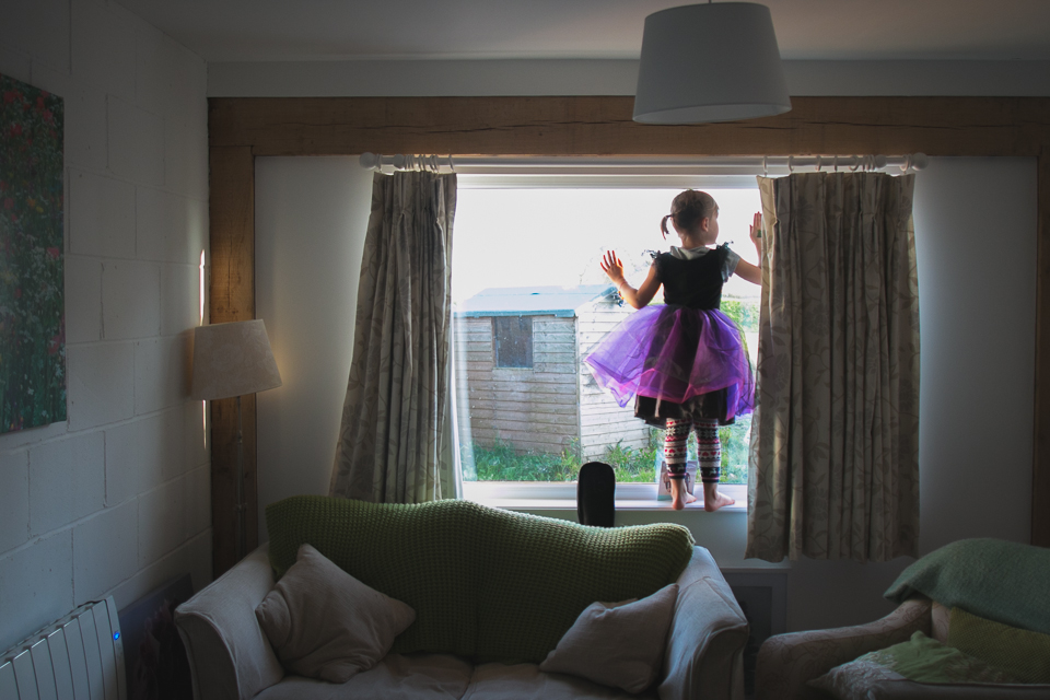 Girls wearing purple tutu standing in window looking out