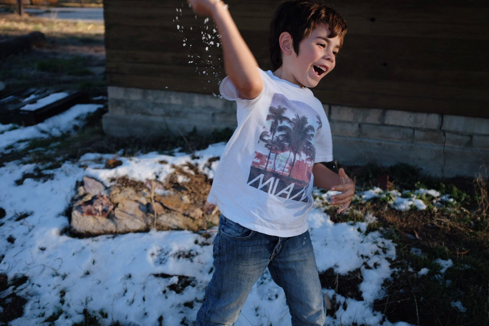 boy wearing tshirt throwing snow