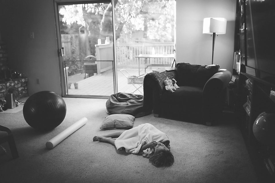 girl lying on loungeroom floor covered with a blanket