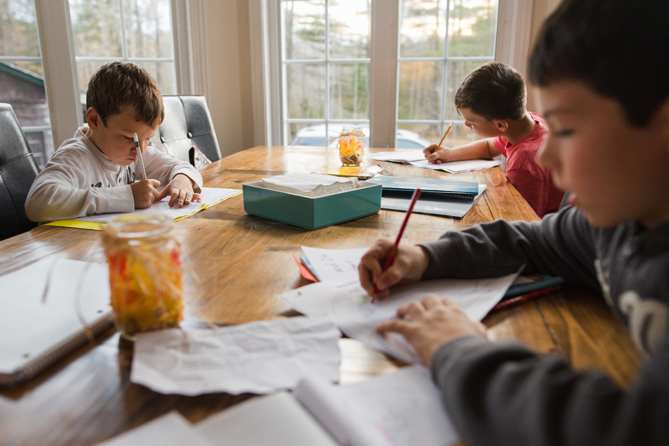 three boys sitting at a table doing homework