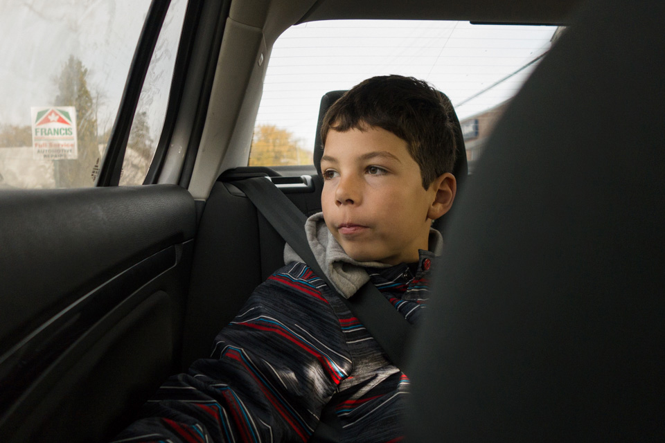 boy looks out car window -family documentary photography