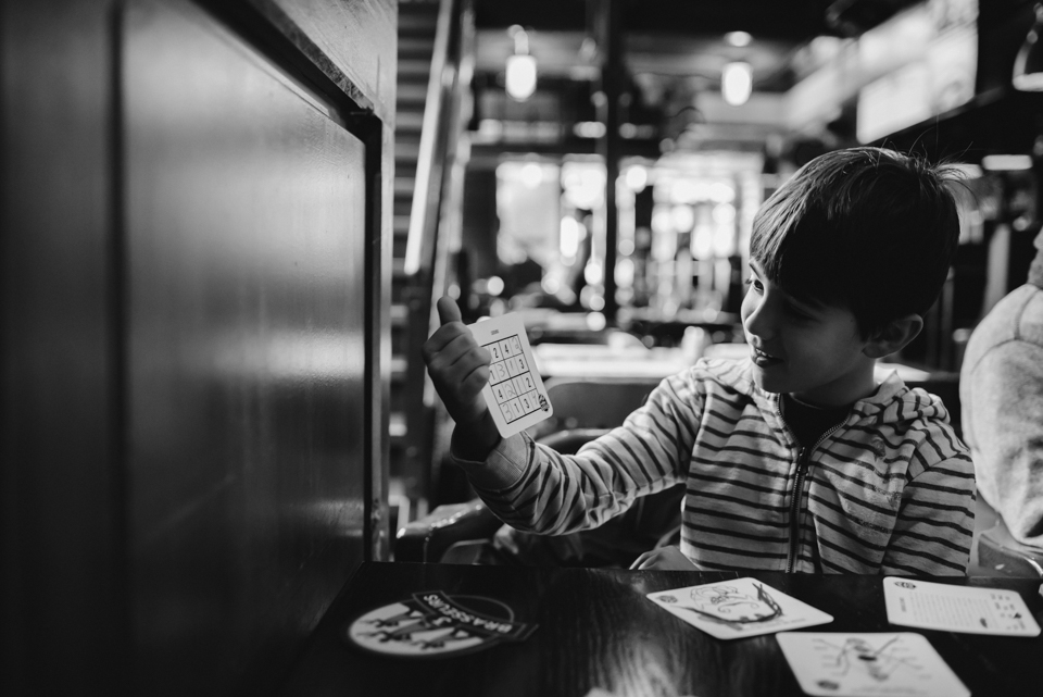 Boy with card game at restaurant - Family Documentary Photography