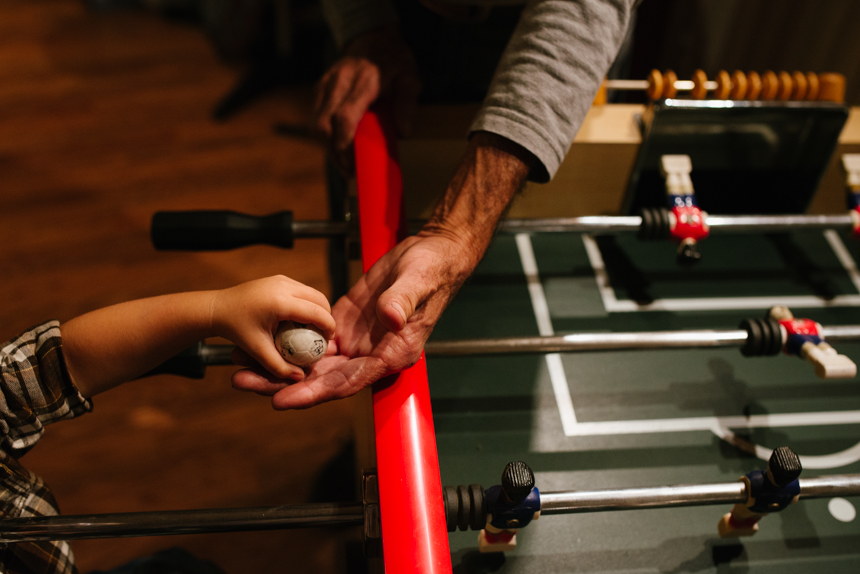 old and young hands with fusseball - Family Documentary Photography