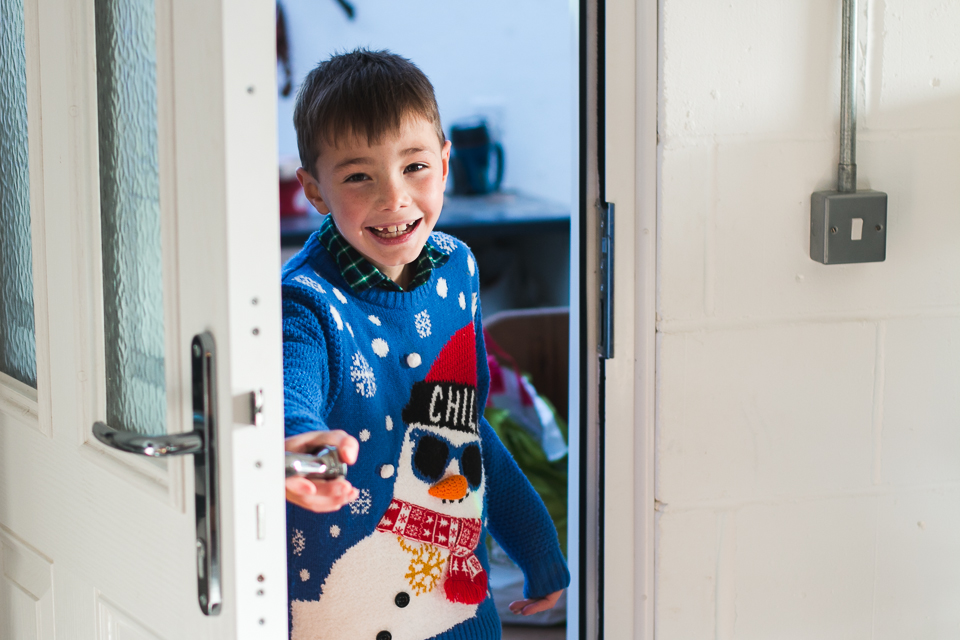 kid with holiday sweater at back door - Family Documentary Photography