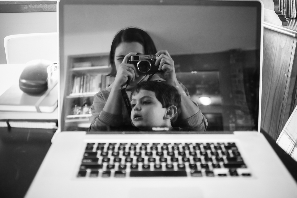Self portrait of mother and boy in laptop reflection