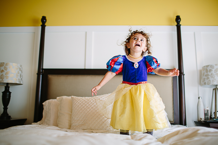 Girl in princess dress jumps on bed - Family Documentary Photography