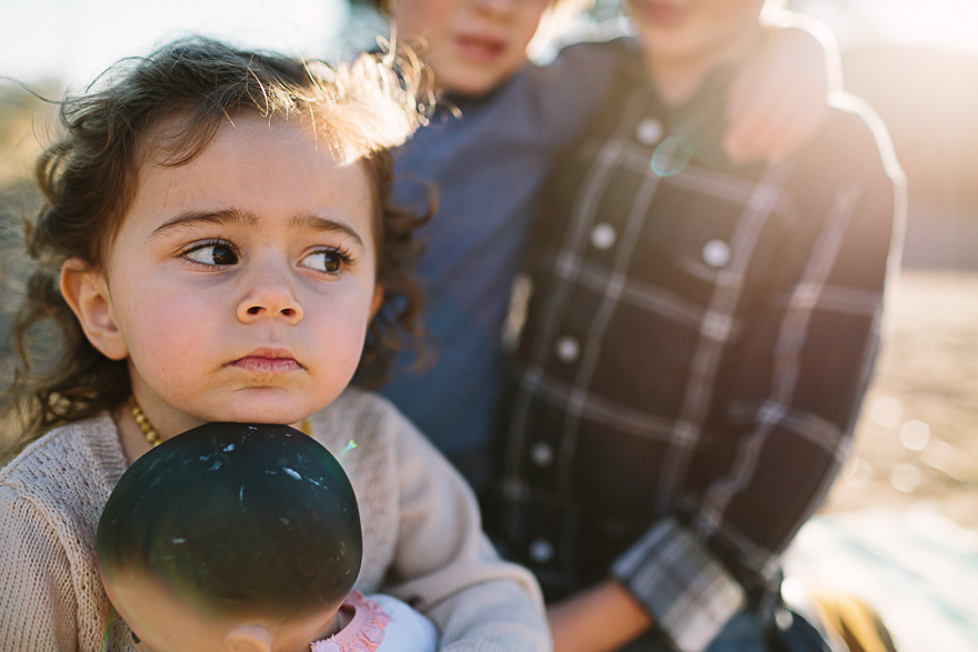 girl holds doll and looks sidelong - Family Documentary Photography