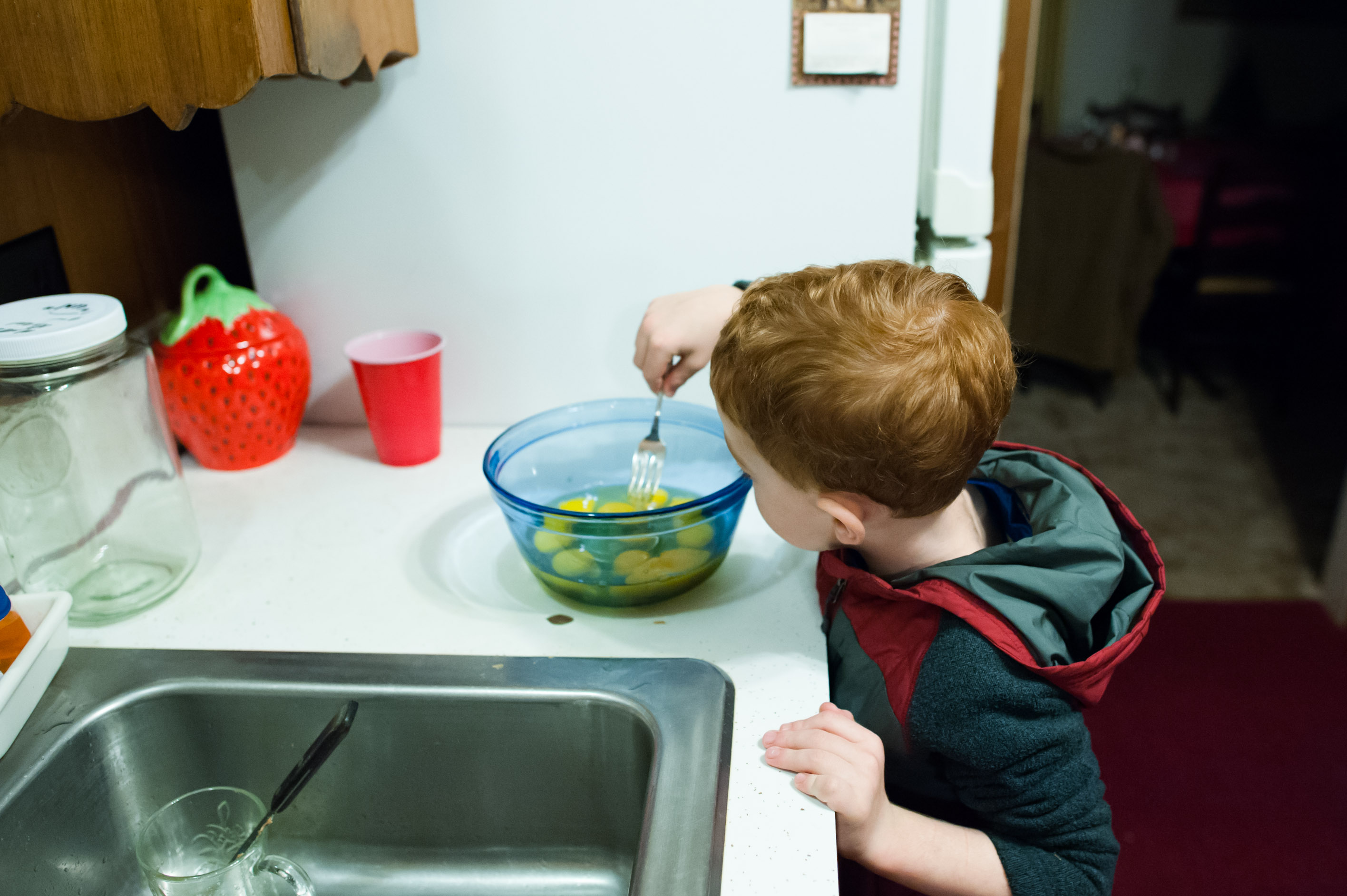 Boy stirs bowl of eggs - Documentary Family Photography