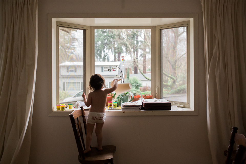 girl watering plants at window - Documentary Family Photography