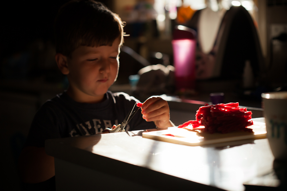 boy using scissors at kitchen counter Family Documentary Photography