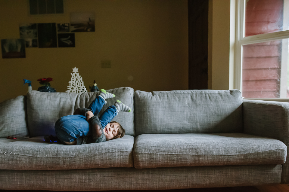 Little boy kicking feet over head on couch