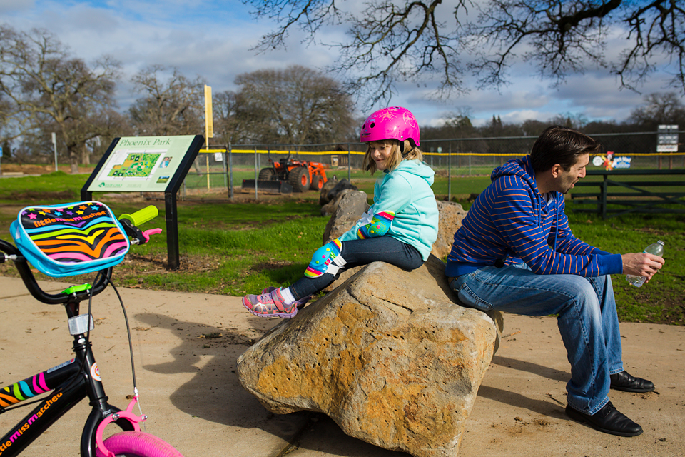 girl with helmet on sitting on rock with dad -Documentary Family Photography