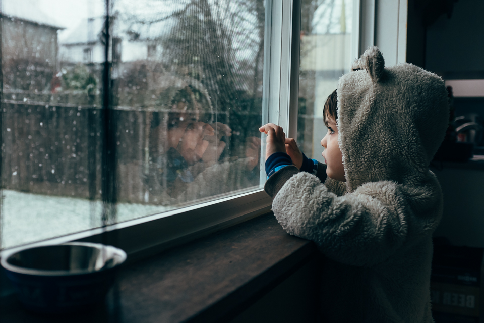 boy at window watching snow - Documentary Family Photography
