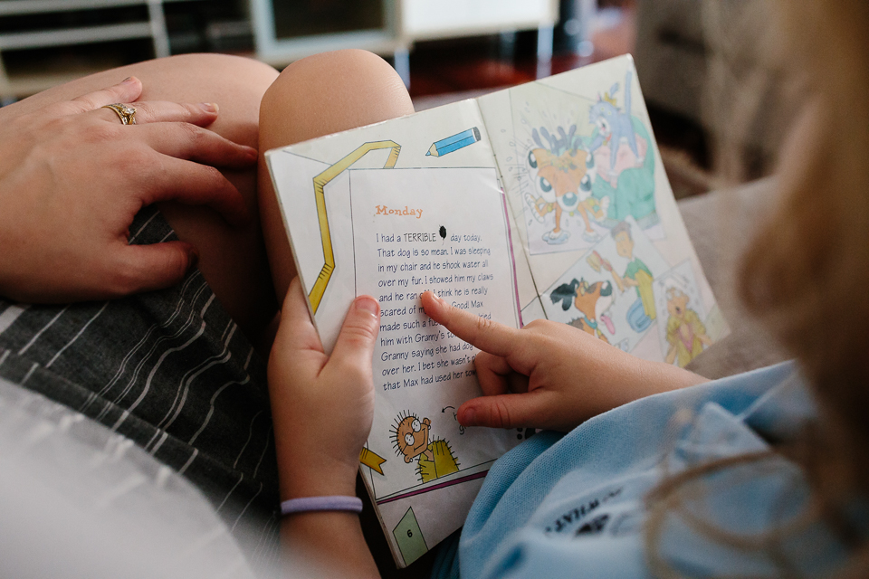 Child reading book next to parent - Documentary Family Photography