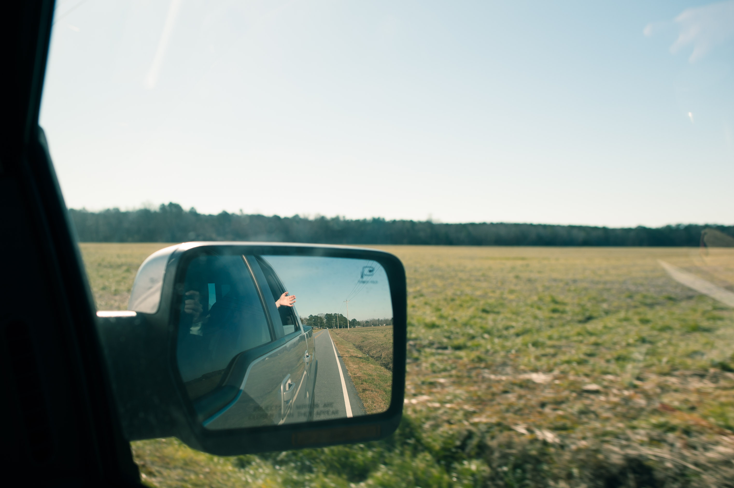 rear view mirror showing child's hand out window - Documentary Family Photography