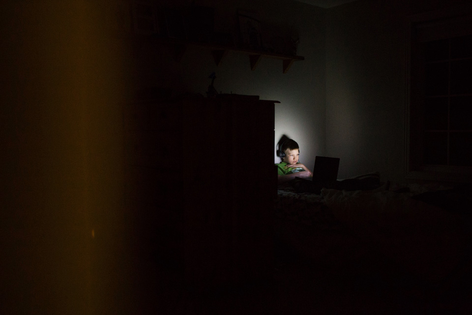 Boy in bed in spot of light - Documentary Family Photography