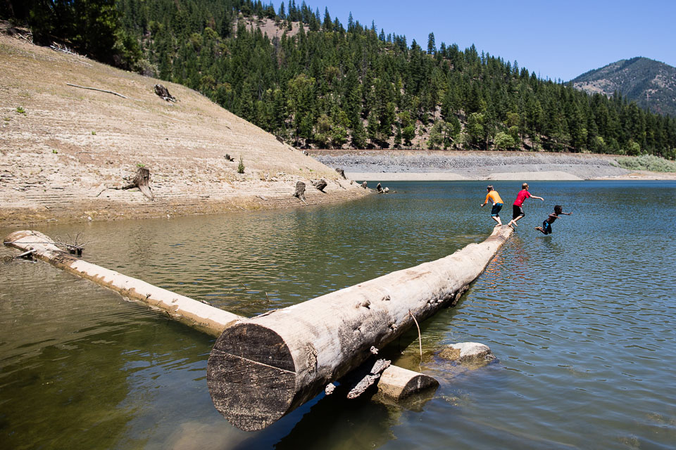 kids jumping off log into lake