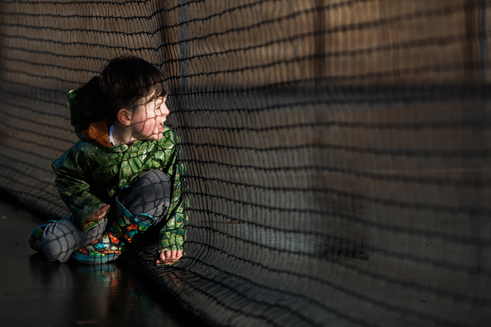 boy looking through netting - Documentary Family Photography