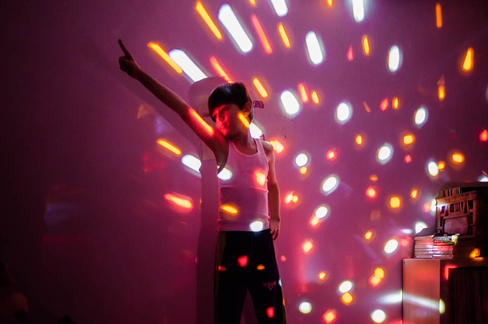 boy in disco pose with lights - Documentary Family Photography