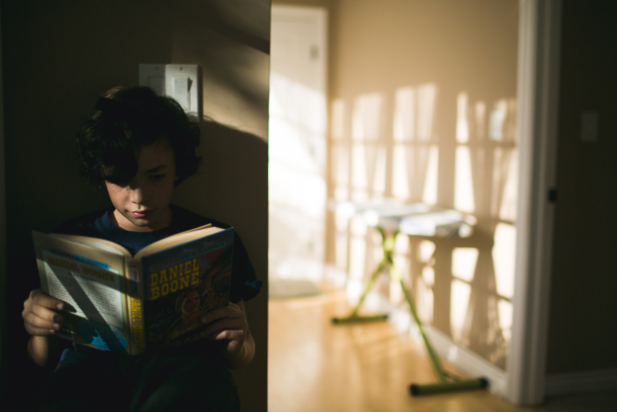 boy reading in dappled light - Documentary Family Photography