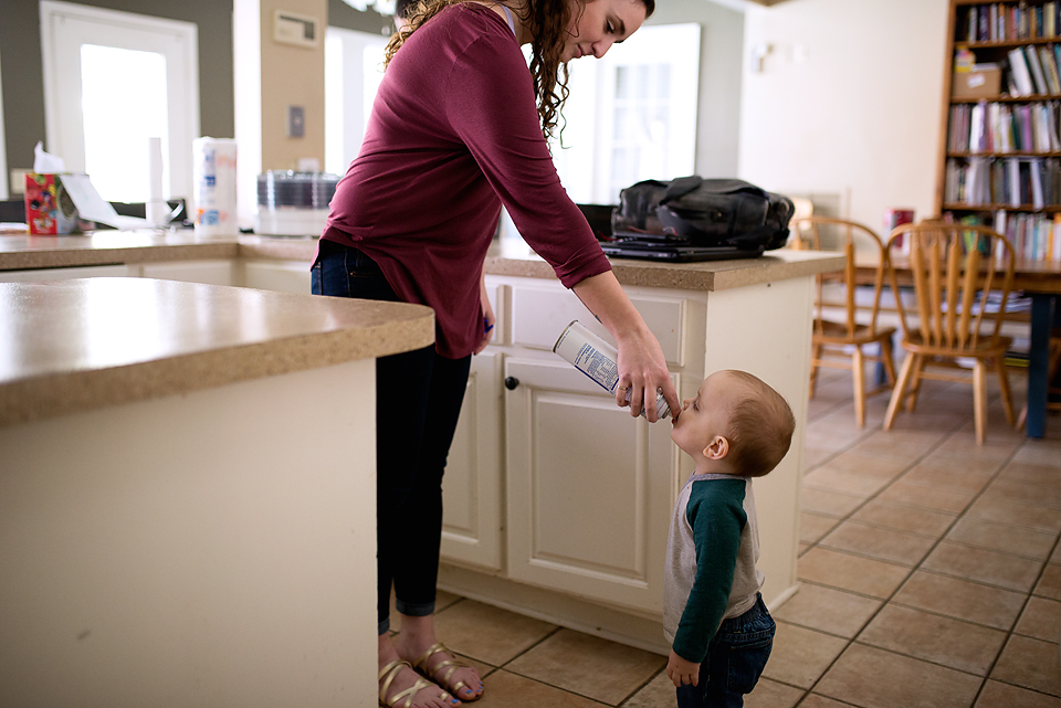 Sister gives toddler boy bottle - Documentary Family Photography