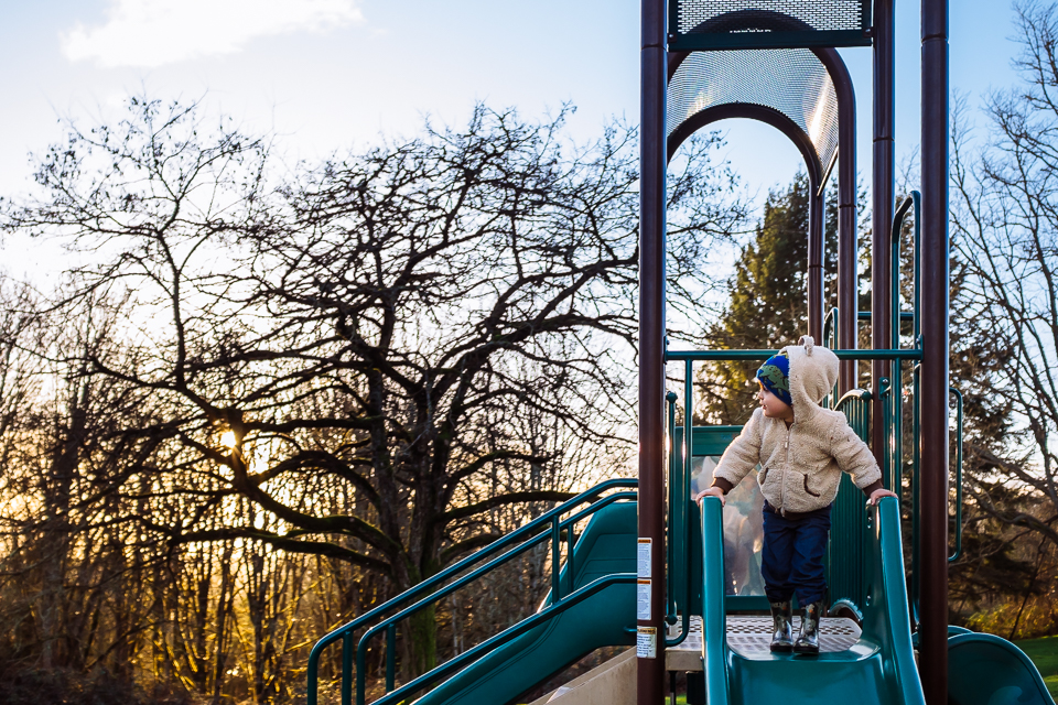 Boy standing at top of slide - Documentary Family Photography