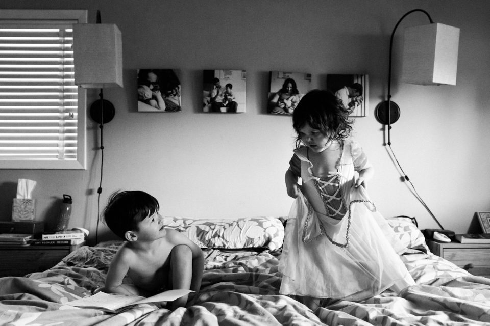 girl in costume with brother on bed - documentary family photography