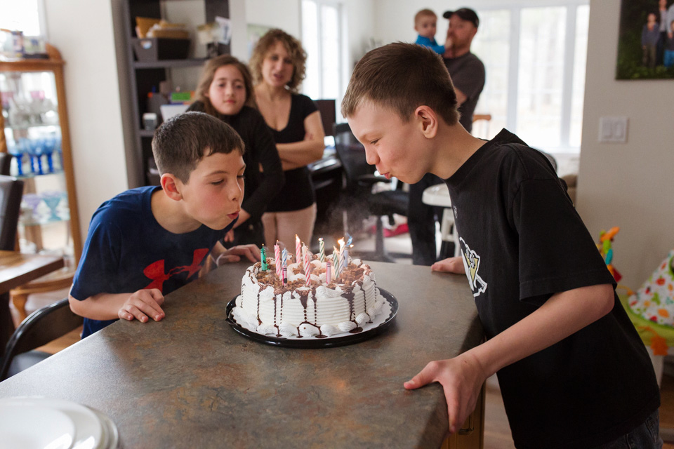 boys blow out candles on birthday cake - documentary family photography