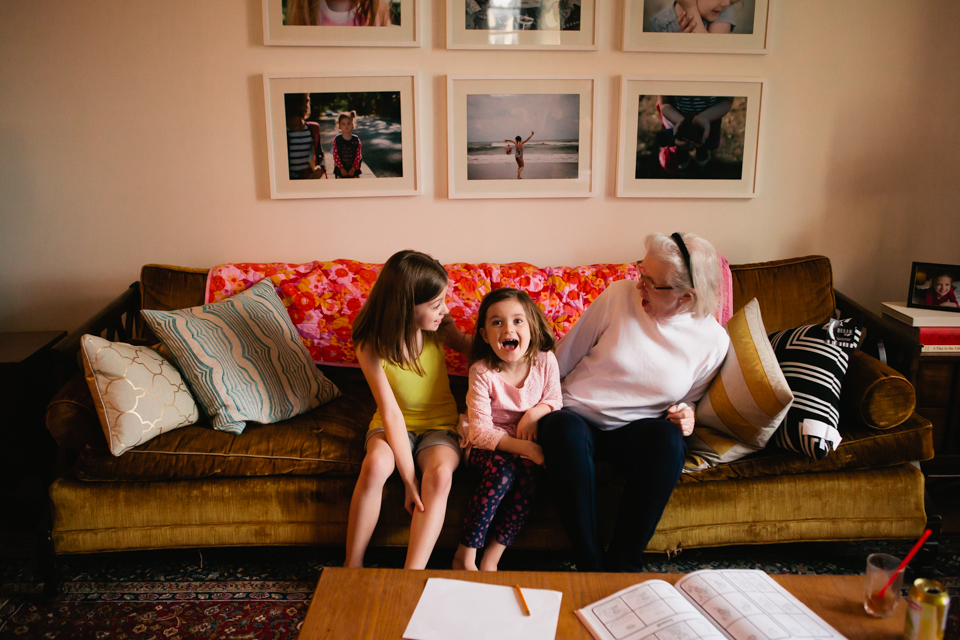 girls laugh with grandmother on couch - Documentary Family Photography