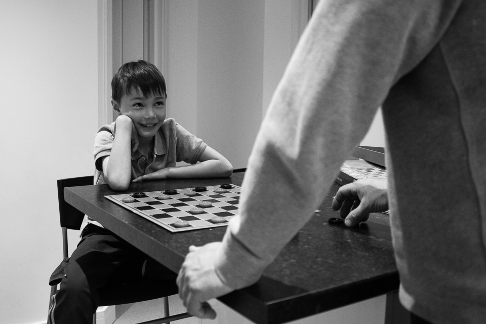 boy and father play checkers - Documentary Family Photography