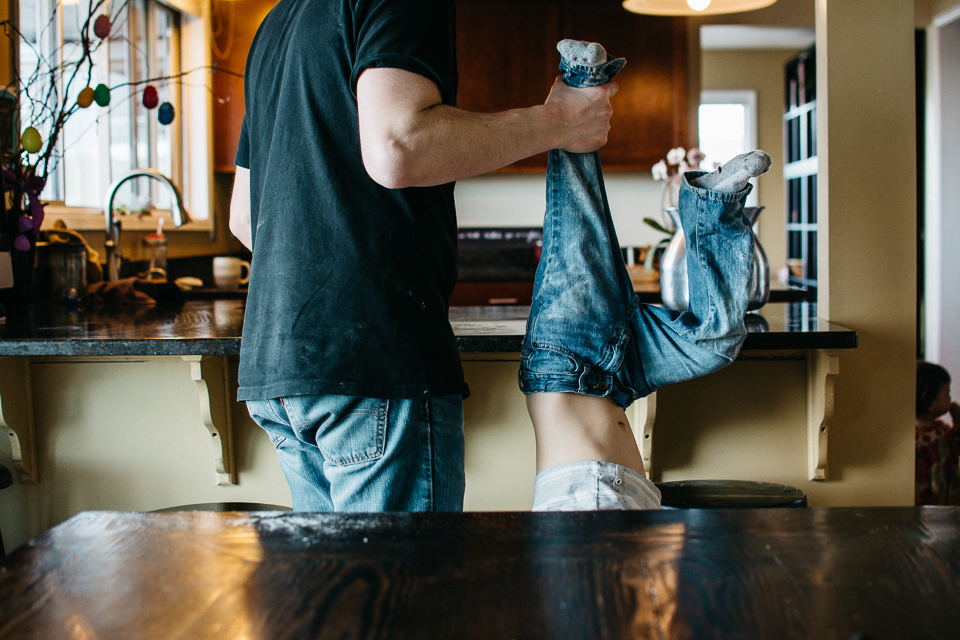 father holds child by ankle - Documentary Family Photography