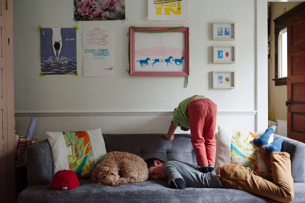 child climbing on sleeping family member - Documentary Family Photography