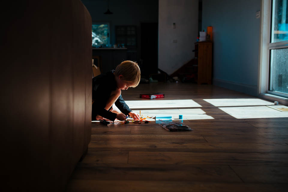boy playing on floor in patch of sunlight - Documentary Family Photography
