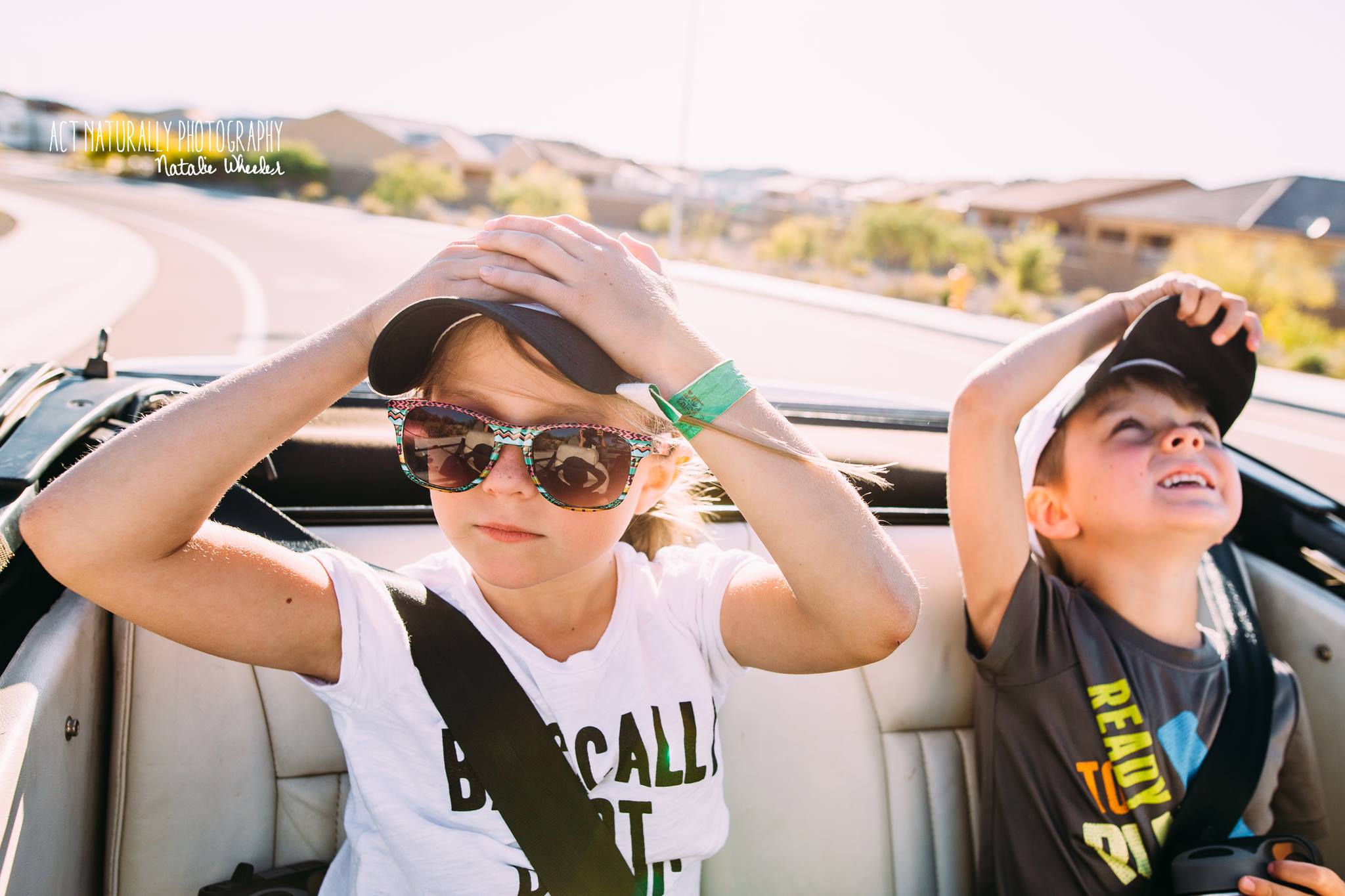 kids hold onto hats while riding in convertible - Documentary Family photography