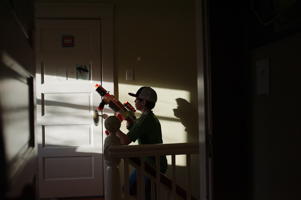 boy with watergun in shadows - Documentary Family Photography